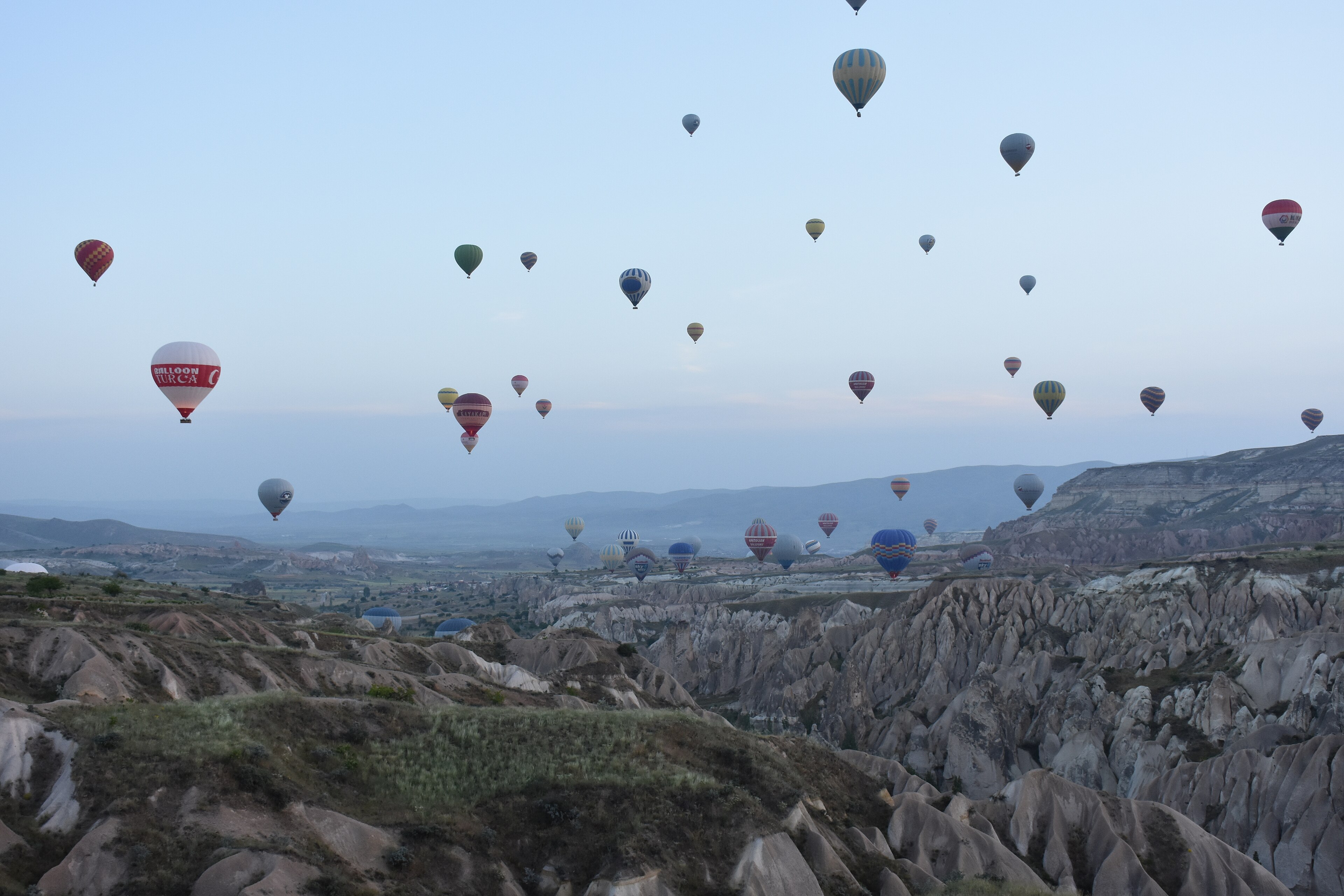 Göreme yakınlarında vadilerin üzerinde şafakta sıcak hava balonları