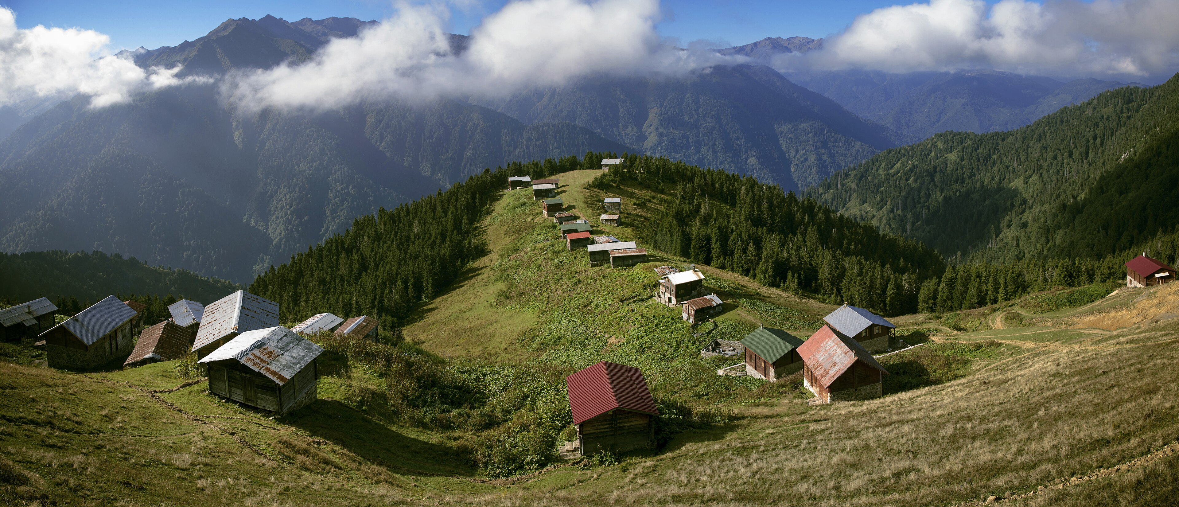 Rize'de bulutlu dağların arasında yemyeşil bir yayla ve yayla evleri